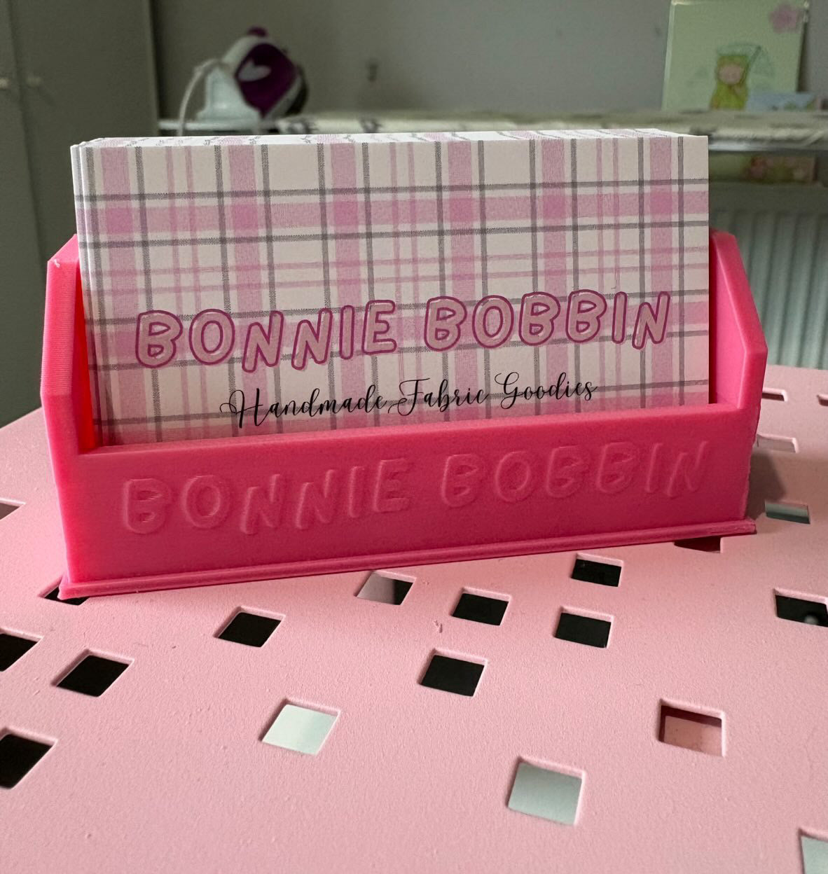 Pink Bonnie Bobbin card holder with a plaid card on a pink surface.