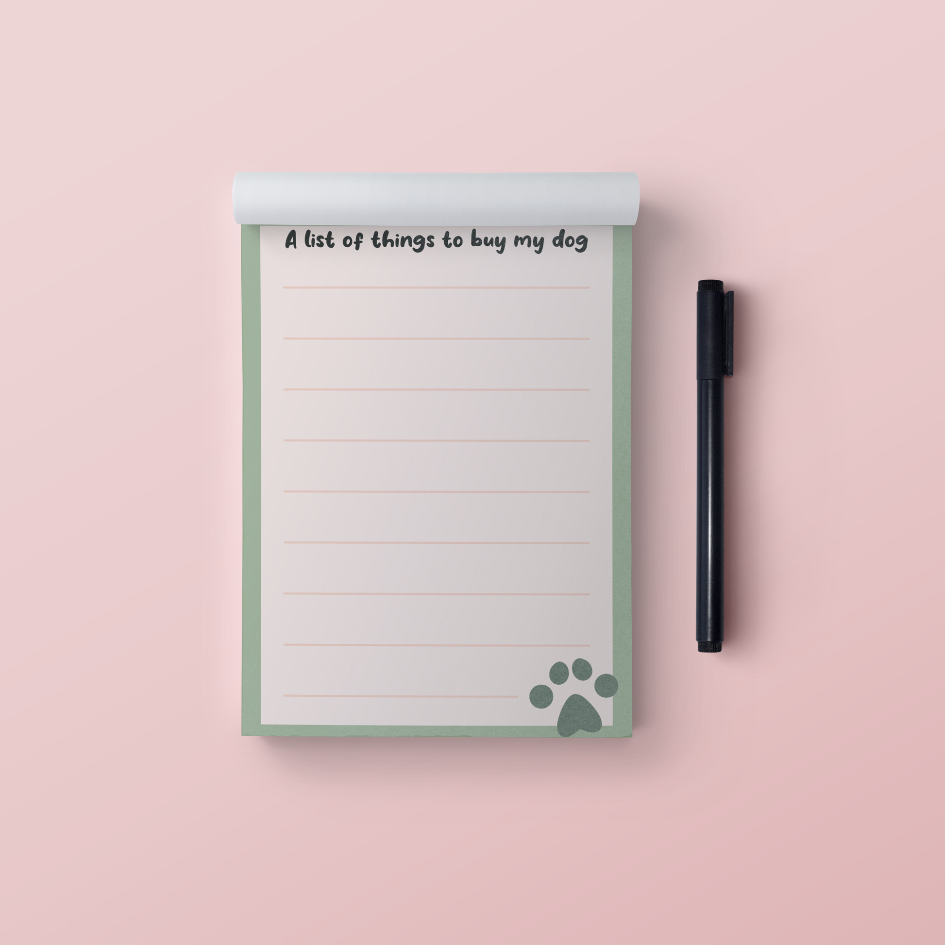 A picture of a green and cream notepad that says A list of things to buy my dog at the top with a green paw print in the bottom right hand corner. Pictured on a pink background with a black pen next to it.